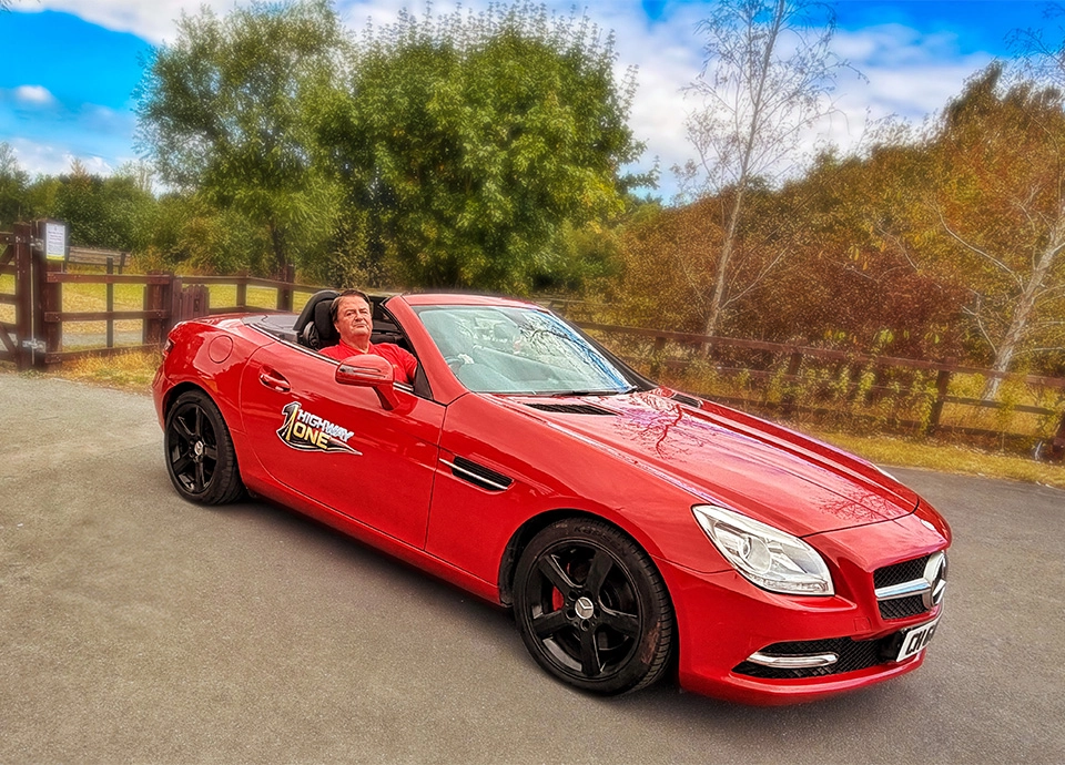 Ivan Hayes sitting in red Mercedes-Benz SLK 250